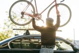 Persona subiendo una bicicleta al techo de un auto