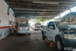 Dos automóviles siendo arreglados al interior de un taller mecánico.