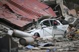 Un automóvil queda aplastado bajo los restos colapsados ​​de un techo de chapa ondulada, entre los escombros, tras un terremoto en Catia La Mar, estado de La Guaira, a unos 30 km al noroeste de Caracas.