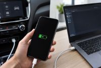 Celular cargando por USB junto a una computadora y un coche cuando falla la transferencia de datos.
