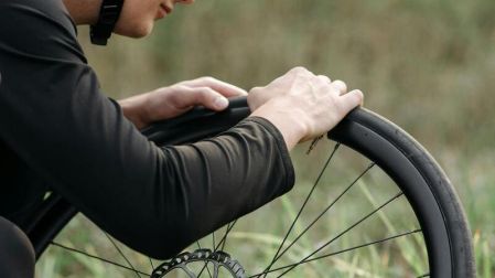 Hombre revisando la rueda y partes de la bicicleta