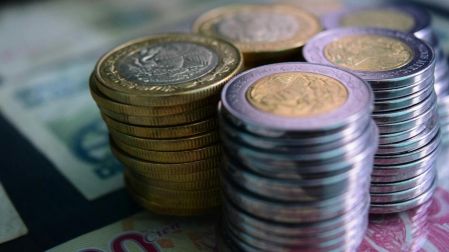 Varias Monedas apiladas entre si sobre unos billetes