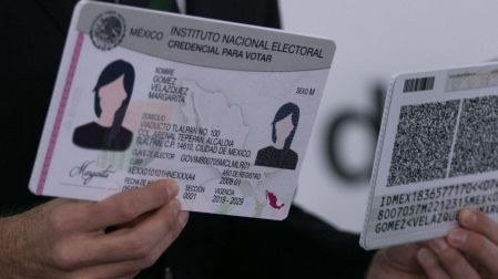 Dos personas sostienen una credencial del INE por ambos lados, documento de identificación oficial para viajes nacionales.