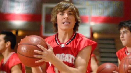 Zac Efron como Troy Bolton en High School Musical, con uniforme rojo de los Wildcats y un balón de basquetbol en las manos.