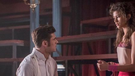 Zac Efron con camisa blanca y tirantes frente a Zendaya, vestida de rosa, durante una escena de El gran showman.