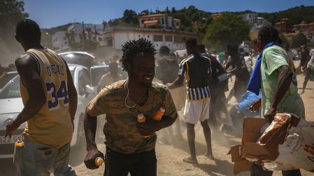 Migrantes, no originarios de Marruecos, reciben jugos desde un automóvil en una playa de Ceuta.