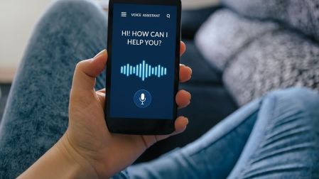 Persona sostiene un celular con un asistente de voz activado en la pantalla.