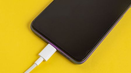 Celular conectado mediante cable USB, utilizado para cargar el dispositivo y transferir archivos a una computadora o coche.