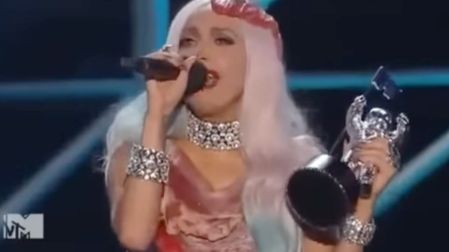 Lady Gaga con vestido de carne, peluca plateada y una estatuilla durante su discurso en los premios MTV de 2010.