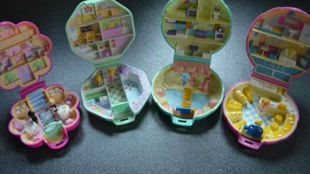 Cuatro estuches clásicos de Polly Pocket abiertos, de colores rosa y verde, con habitaciones, muebles y pequeñas muñecas.
