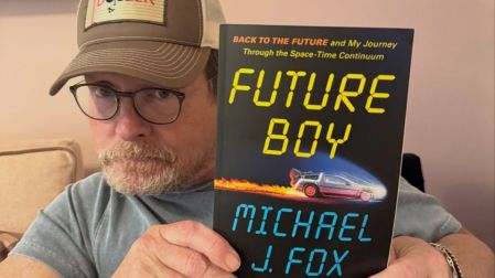 Michael J. Fox sostiene su libro Future Boy, cuya portada muestra el DeLorean de Volver al futuro.