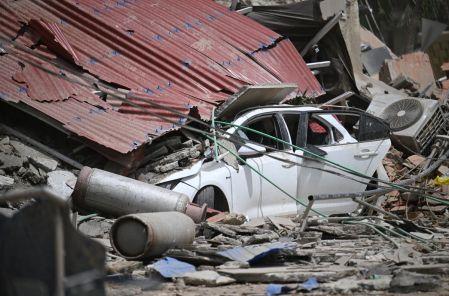 Un automóvil queda aplastado bajo los restos colapsados ​​de un techo de chapa ondulada, entre los escombros, tras un terremoto en Catia La Mar, estado de La Guaira, a unos 30 km al noroeste de Caracas.