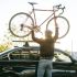 Persona subiendo una bicicleta al techo de un auto