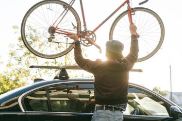 Persona subiendo una bicicleta al techo de un auto