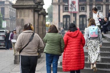 Tres personas caminando por el Valle de Toluca, abrigadas ante las bajas temperaturas.