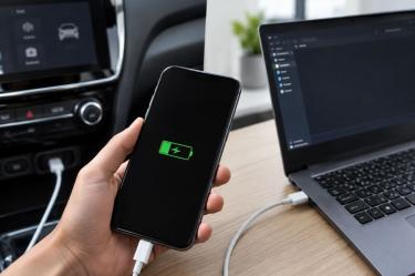 Celular cargando por USB junto a una computadora y un coche cuando falla la transferencia de datos.
