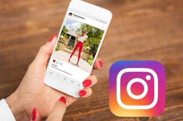 Persona utiliza Instagram en un teléfono celular junto al logotipo actual de la red social.